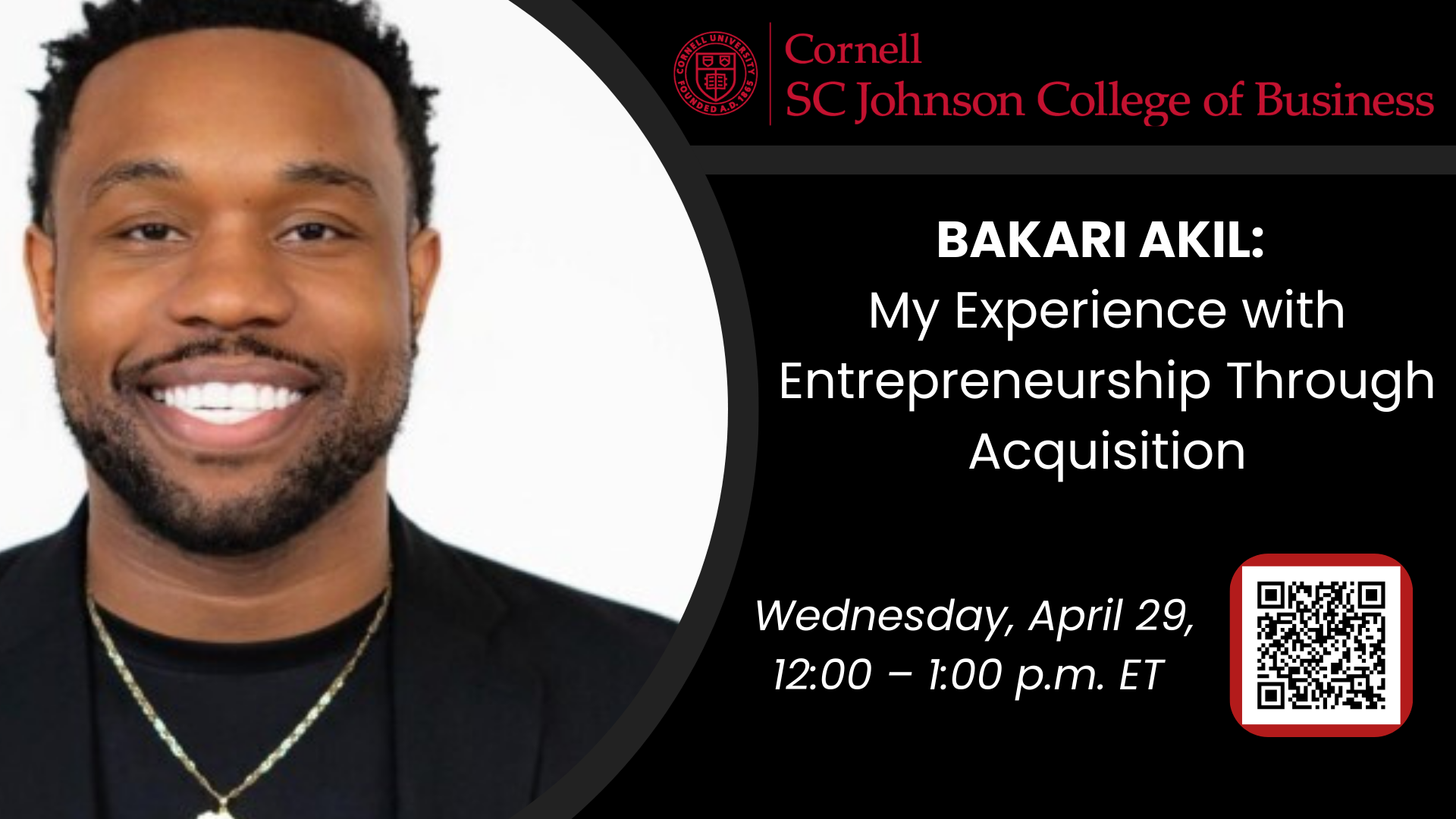 Young African-American man with a beard and big smile on his face. He's wearing a silver necklace and black suit.