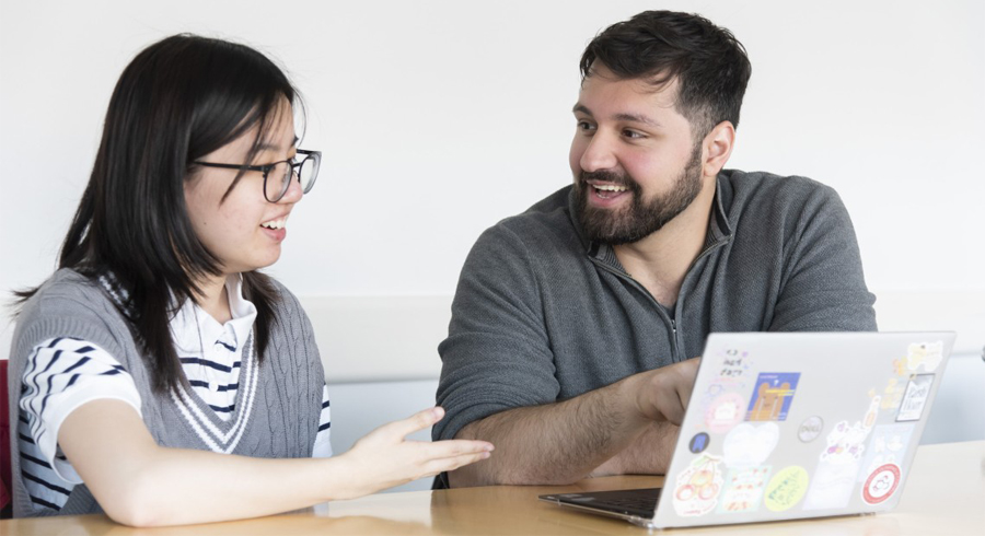 Farid Aboharb, right, and Diran Tan '25 study the effects of psychiatric drugs on gene expression. A female and a male student sitting at a table talking. The male student is pointing to the screen of a laptop.