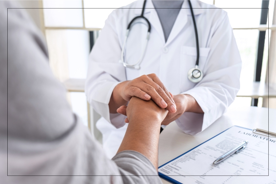 A doctor in a white coat holding a patient's hand