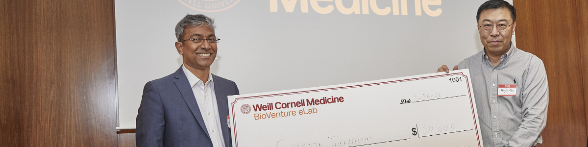 First prize winner (two Asian men) of BioVenture eLab's Business Plan Challenge Pitch Competition holding a giant check