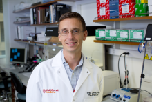 Caucasian man wearing glasses and a white coat in a lab