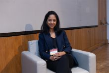 Dr. Erandi De Silva. A woman in dark blue suit and pants sitting in a sofa.