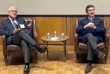 Two Caucasian men in dark-colored business attire sitting on sofas