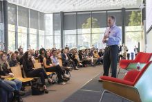 A man presenting to a group of audience in a large conference room