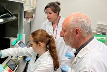 Dr. Stephen Kaminsky (right) and Two Facility Members (Provided) Three researchers (two women and a men on the right) wearing white coats in a lab