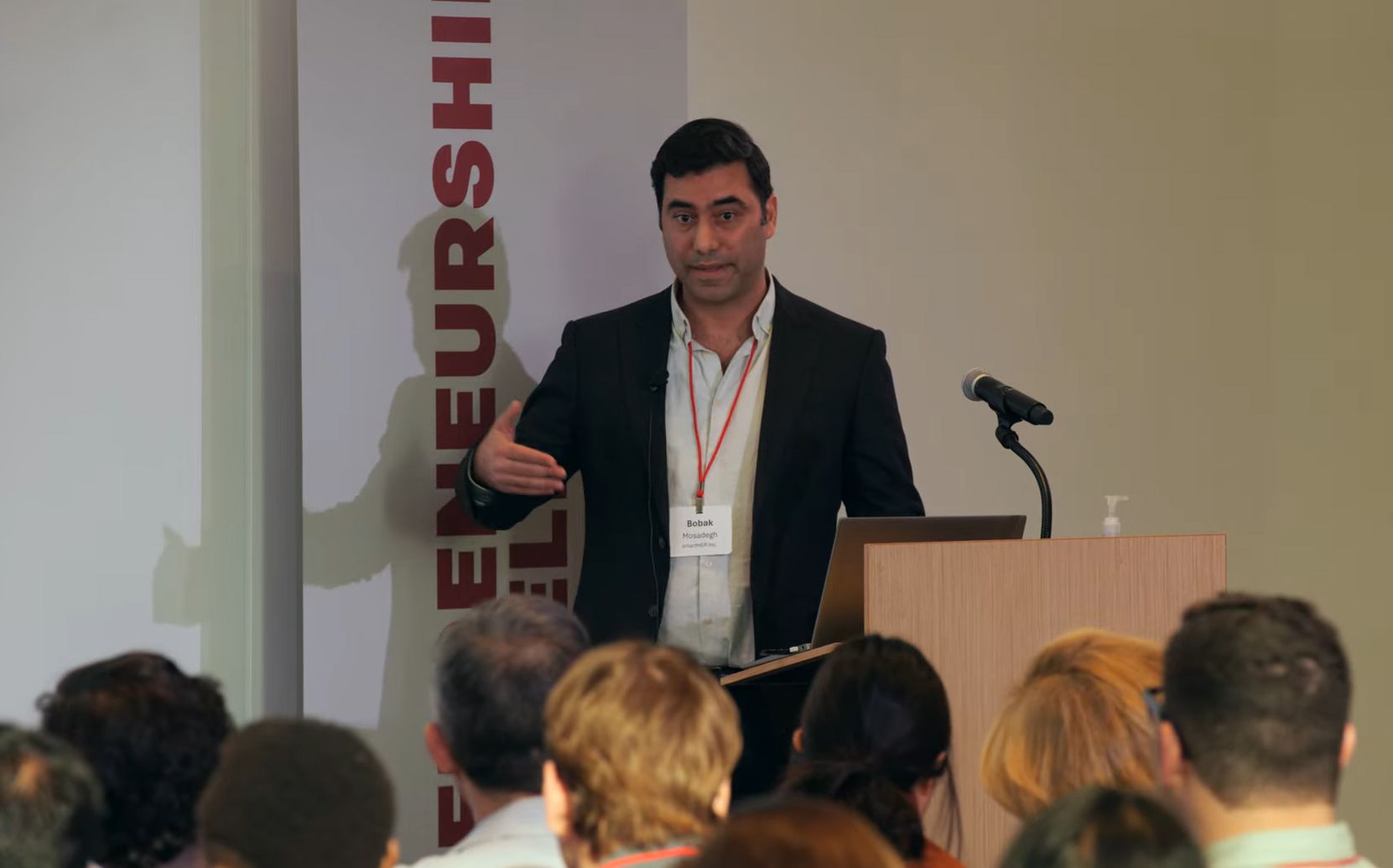A man in a white shirt and black suit talking to an audience