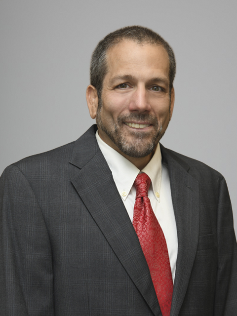 Middle-aged Caucasian man wearing a red tie and dark gray suit